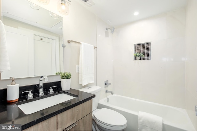 full bathroom featuring tiled shower / bath, vanity, and toilet