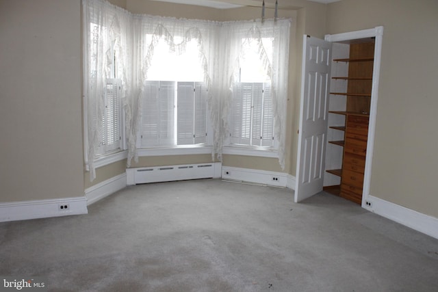 empty room featuring a baseboard heating unit and carpet flooring