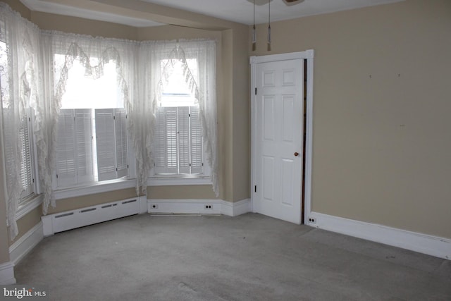 carpeted empty room featuring baseboard heating and ceiling fan