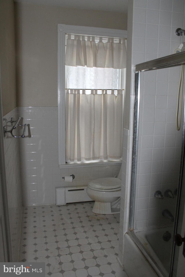 bathroom featuring baseboard heating, enclosed tub / shower combo, tile walls, and toilet