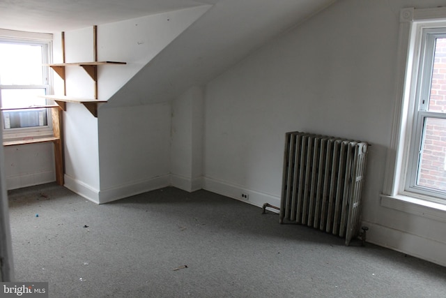 additional living space featuring lofted ceiling and radiator heating unit