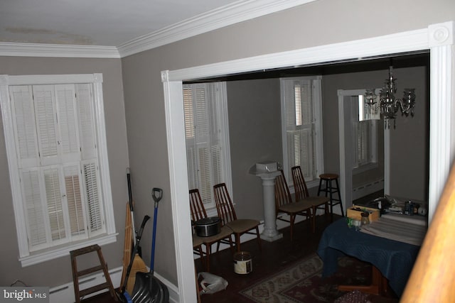 living area with crown molding, baseboard heating, and an inviting chandelier