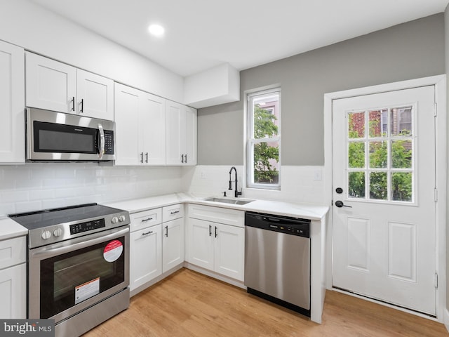 kitchen with decorative backsplash, sink, white cabinetry, and appliances with stainless steel finishes