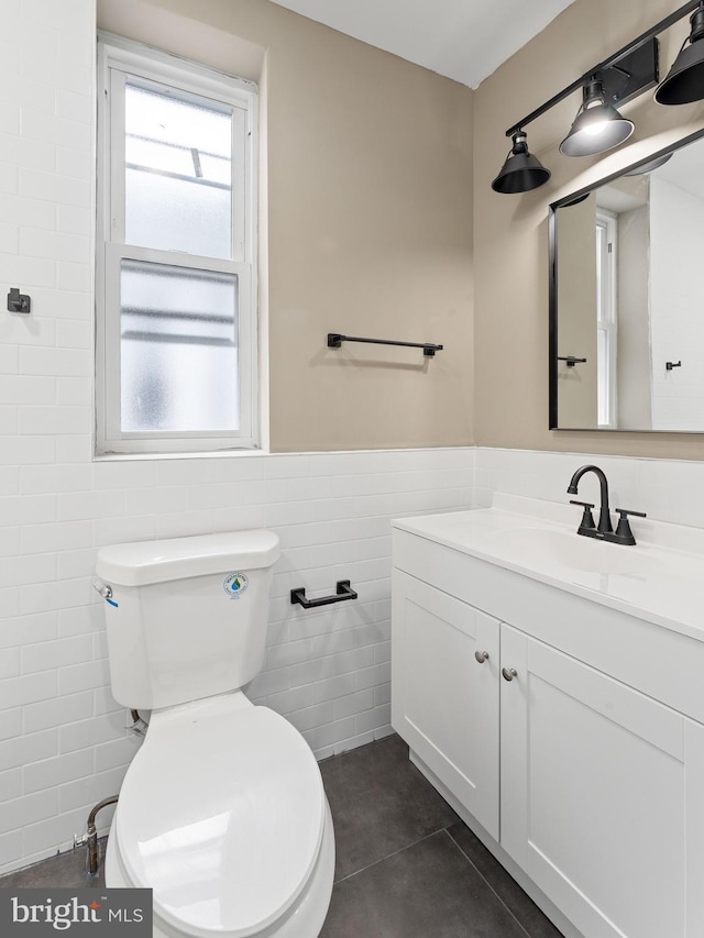 bathroom with toilet, tile walls, and vanity