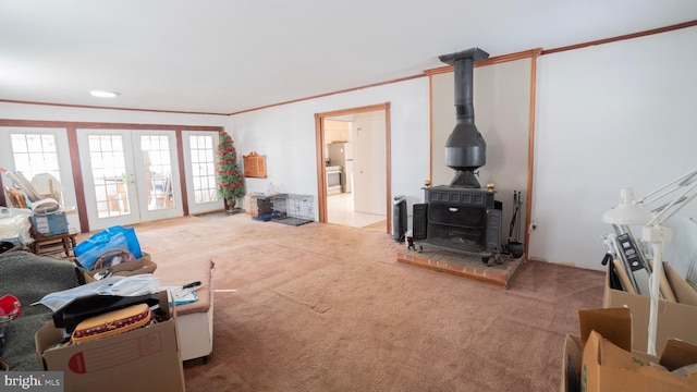 carpeted living room with ornamental molding, a wood stove, and french doors