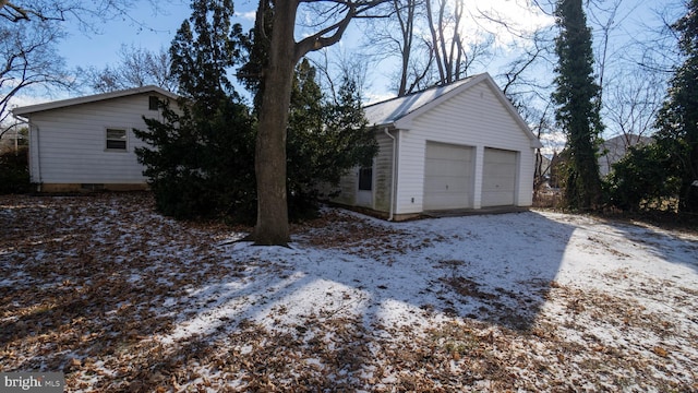 view of snowy exterior with a garage and an outdoor structure