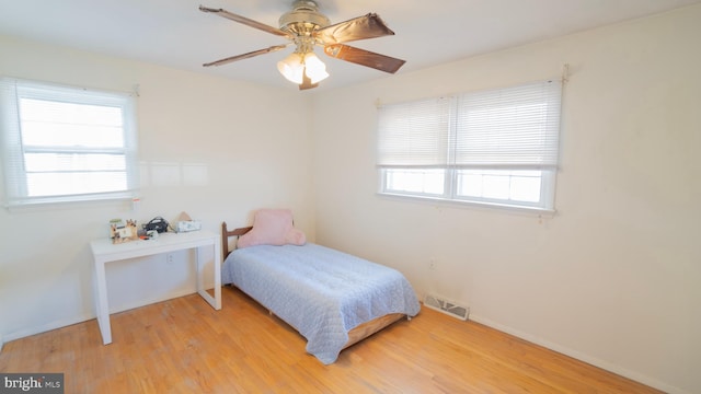 bedroom featuring multiple windows, light hardwood / wood-style floors, and ceiling fan