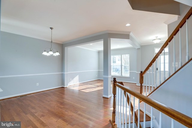 interior space with an inviting chandelier, wood-type flooring, and ornamental molding