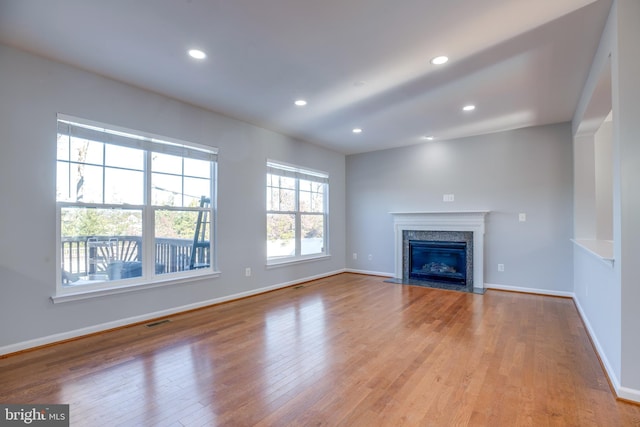 unfurnished living room with a high end fireplace and light hardwood / wood-style flooring