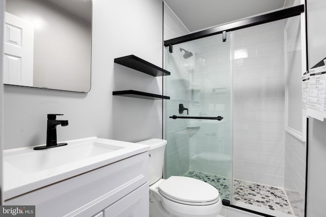 bathroom with a shower with door, vanity, and toilet