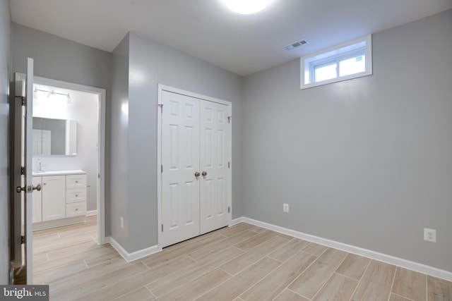 unfurnished bedroom with ensuite bathroom, sink, light hardwood / wood-style floors, and a closet