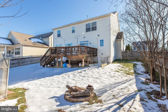 snow covered house featuring a deck and an outdoor fire pit