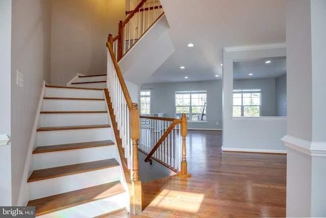 stairway with crown molding and hardwood / wood-style floors