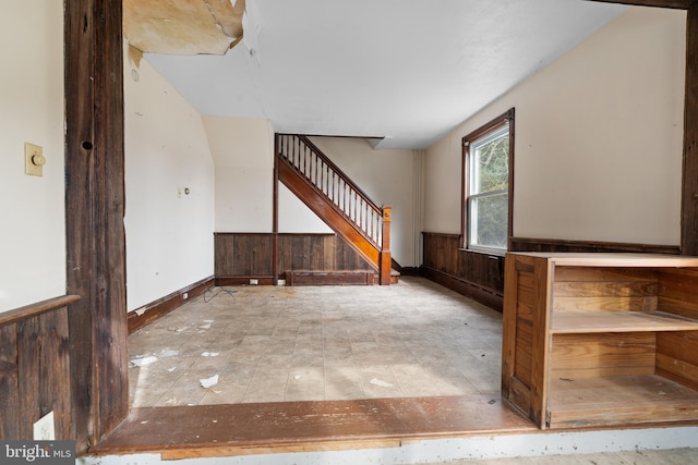 unfurnished living room with wood walls