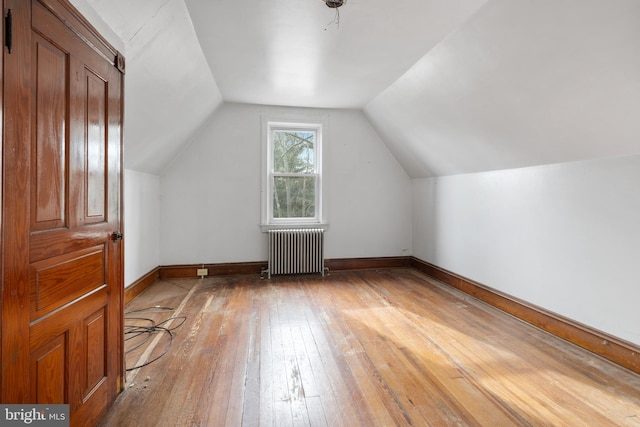 bonus room featuring vaulted ceiling, radiator heating unit, and hardwood / wood-style floors