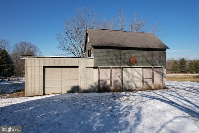 view of snow covered exterior featuring a garage and an outdoor structure