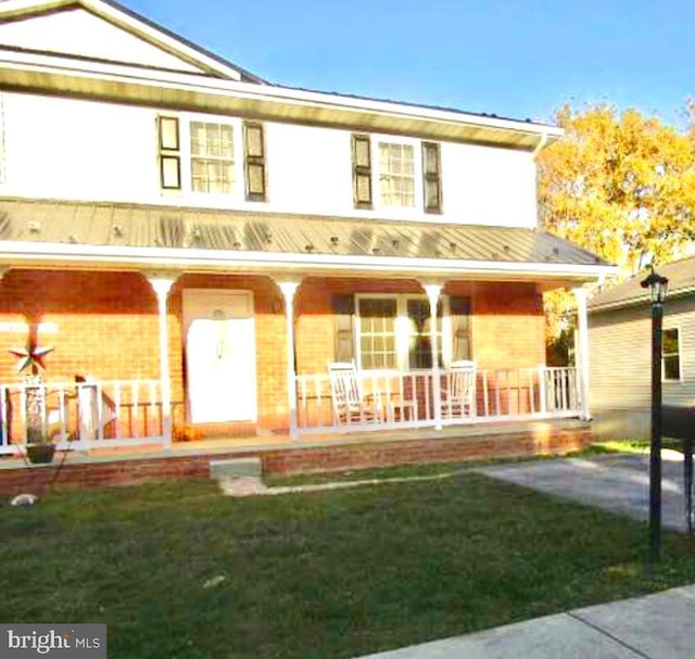 rear view of house featuring a porch and a lawn