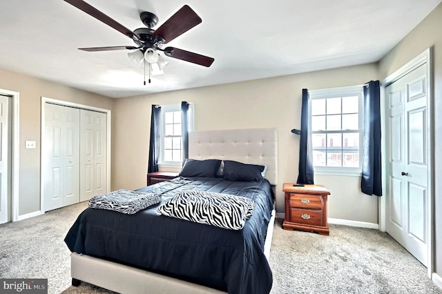 bedroom featuring two closets, ceiling fan, and carpet flooring