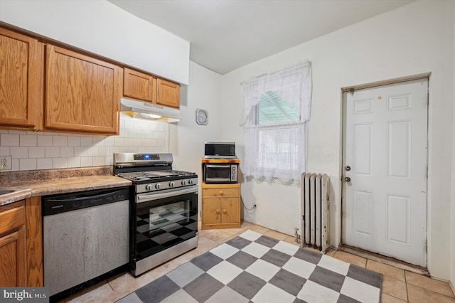 kitchen featuring decorative backsplash, light tile patterned floors, radiator, and stainless steel appliances