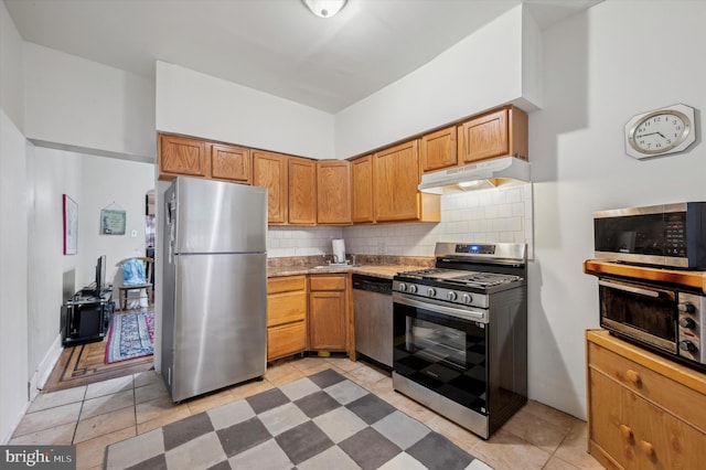 kitchen with decorative backsplash, appliances with stainless steel finishes, and light tile patterned flooring