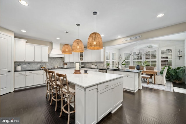 kitchen with premium range hood, white cabinetry, a kitchen island, and hanging light fixtures