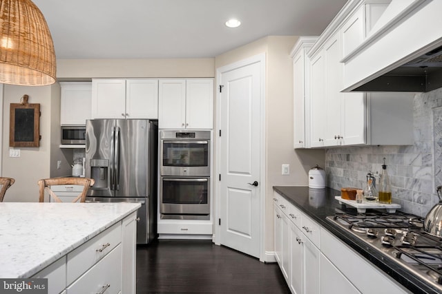 kitchen featuring appliances with stainless steel finishes, tasteful backsplash, white cabinetry, custom exhaust hood, and light stone countertops