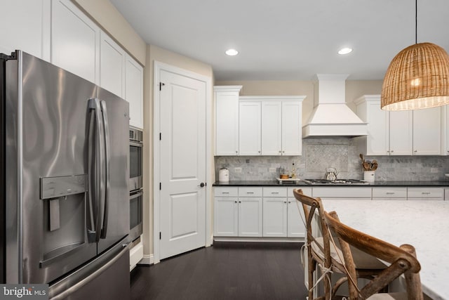 kitchen with pendant lighting, white cabinetry, custom range hood, and appliances with stainless steel finishes