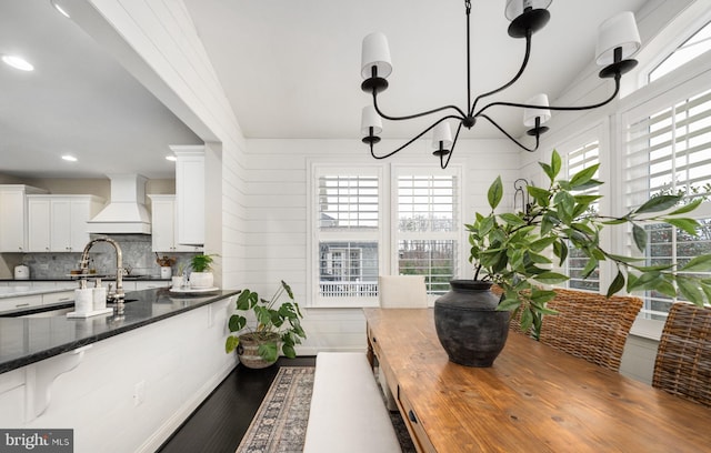 kitchen with decorative light fixtures, custom range hood, a wealth of natural light, dark stone counters, and white cabinets