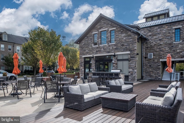 wooden deck with an outdoor living space and a bar