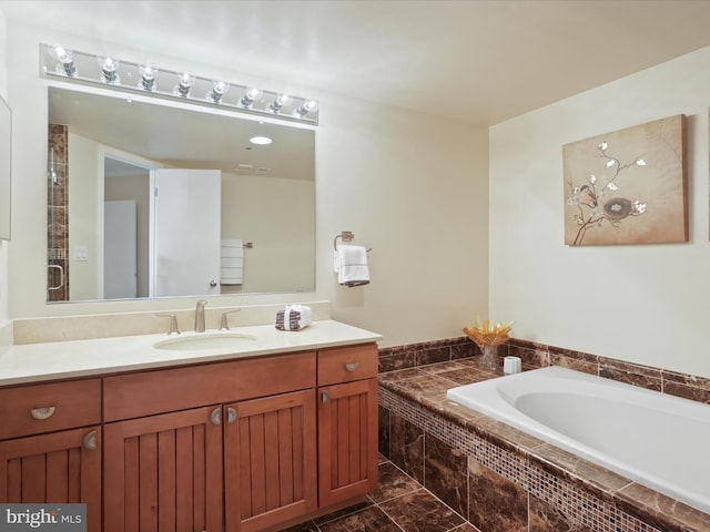 bathroom with vanity and tiled bath