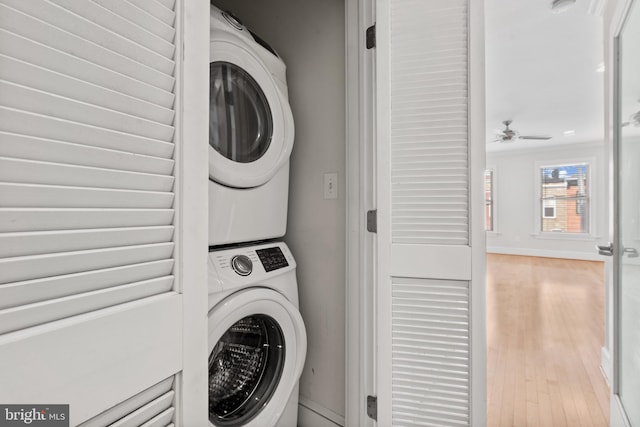 laundry area with stacked washer / drying machine, ceiling fan, and light hardwood / wood-style flooring