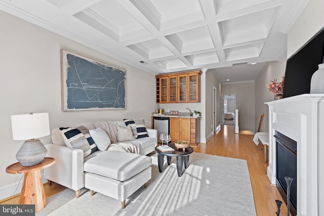 living room featuring beamed ceiling, indoor bar, crown molding, coffered ceiling, and light hardwood / wood-style flooring