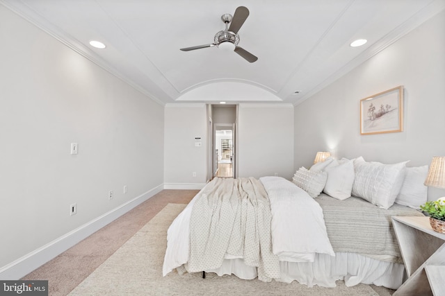 carpeted bedroom with ceiling fan, a raised ceiling, and ornamental molding