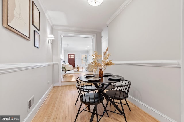 dining area featuring ornamental molding and light wood-type flooring