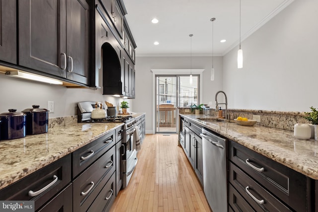 kitchen with light stone countertops, appliances with stainless steel finishes, decorative light fixtures, sink, and ornamental molding