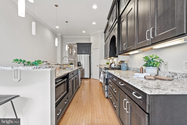 kitchen with appliances with stainless steel finishes, decorative light fixtures, sink, light wood-type flooring, and crown molding