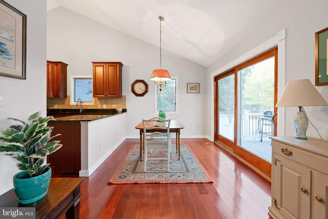 dining space featuring dark wood-type flooring, sink, a chandelier, and vaulted ceiling