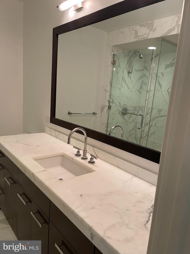 bathroom with a shower with shower door and vanity