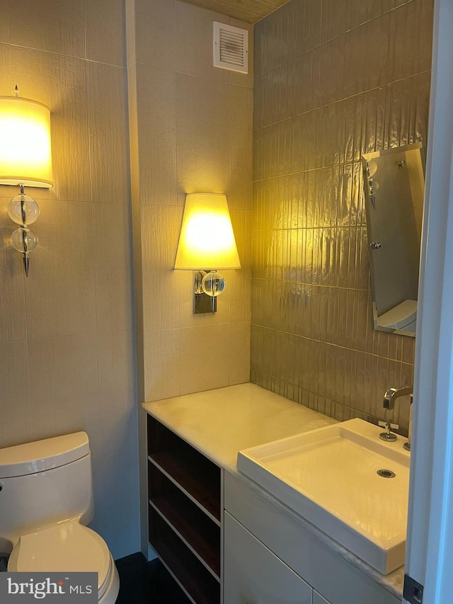 bathroom featuring backsplash, toilet, vanity, and tile walls