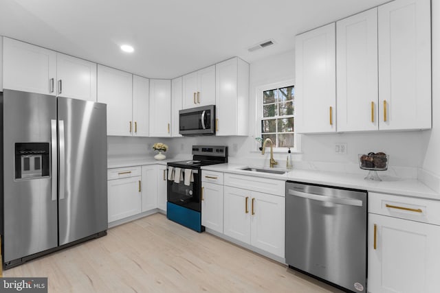 kitchen with white cabinets, sink, stainless steel appliances, and light hardwood / wood-style floors