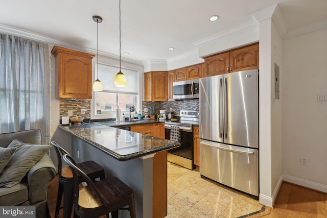 kitchen with appliances with stainless steel finishes, backsplash, pendant lighting, dark stone counters, and crown molding