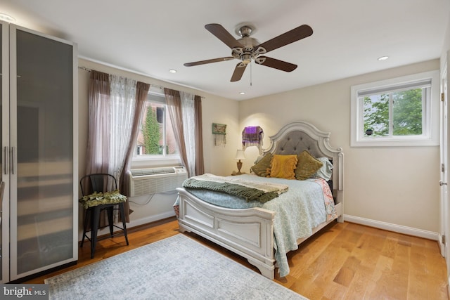 bedroom with ceiling fan, cooling unit, and light hardwood / wood-style flooring