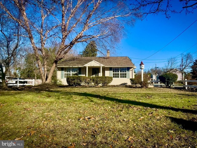 ranch-style home with a front lawn, a chimney, and fence