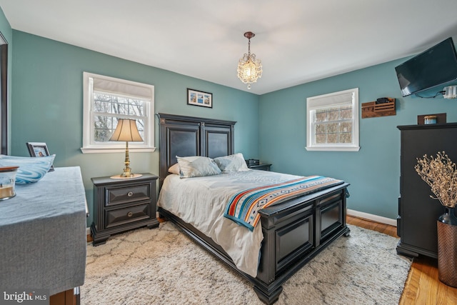 bedroom with light wood-type flooring, multiple windows, and baseboards