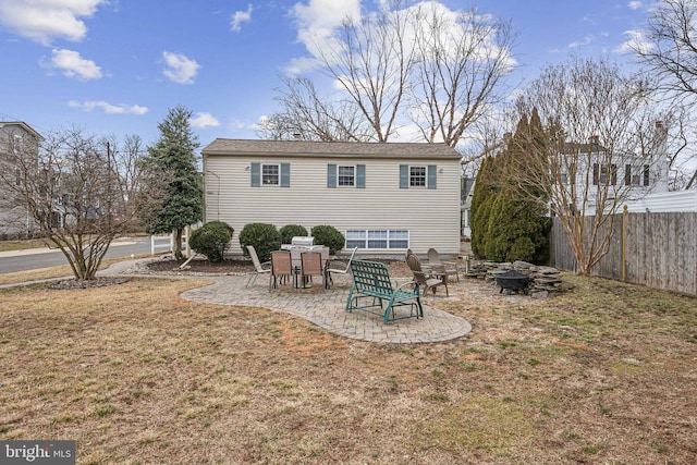 back of property featuring an outdoor fire pit, fence, a lawn, and a patio