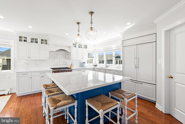 kitchen with paneled built in fridge, white cabinets, a healthy amount of sunlight, and a center island