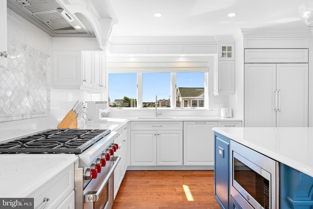 kitchen with sink, built in appliances, white cabinetry, light hardwood / wood-style flooring, and custom range hood