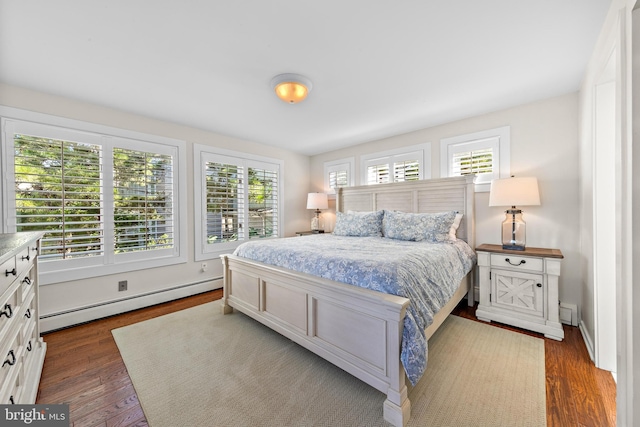 bedroom featuring a baseboard heating unit, dark hardwood / wood-style flooring, and multiple windows