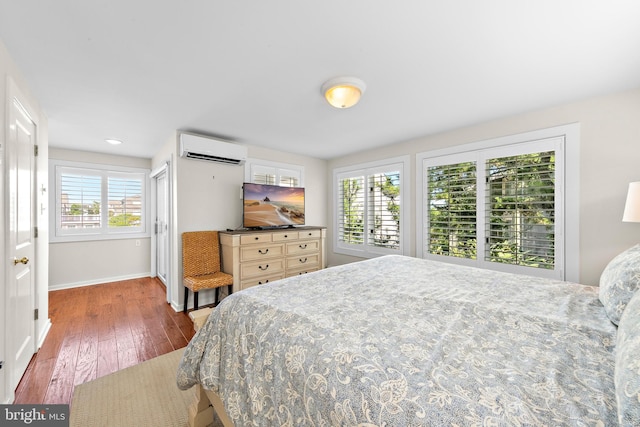 bedroom featuring dark wood-type flooring, multiple windows, and a wall mounted air conditioner