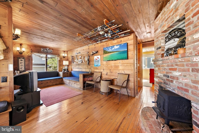 living room with hardwood / wood-style floors, wooden walls, a wood stove, and wooden ceiling